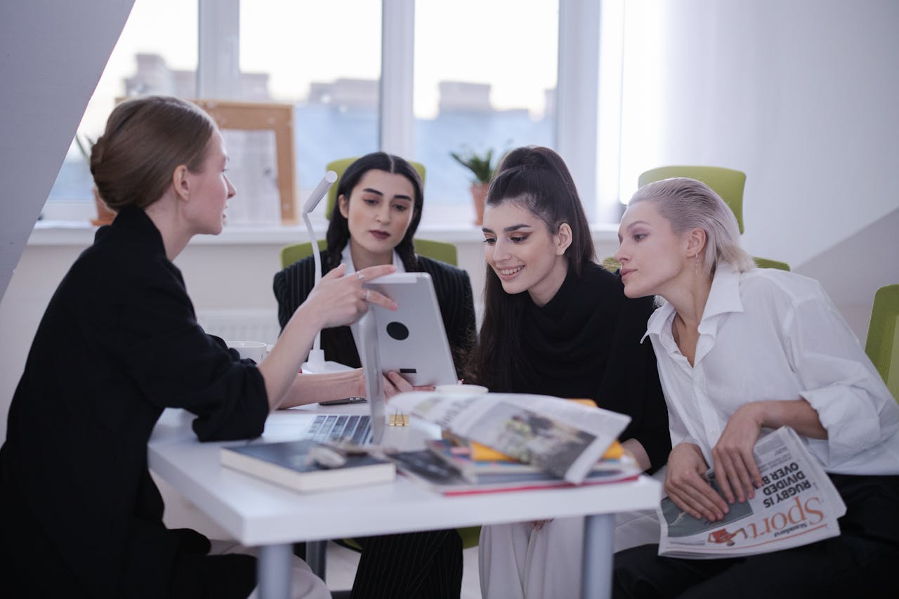 Four women engage in a creative brainstorming session around a table in a bright office.